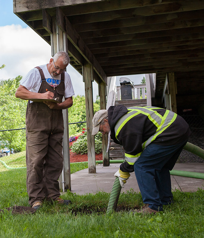 Guy inspecting septic tank while it is being pumped