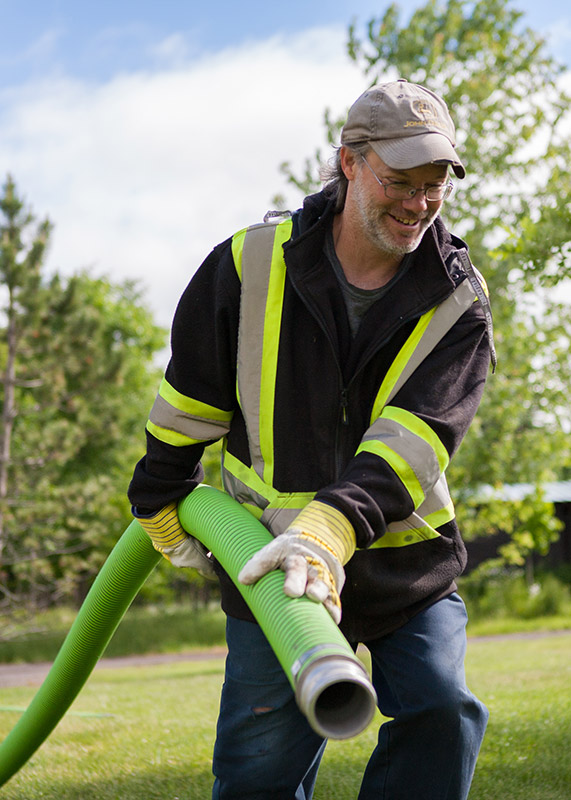 Guy dragging hose from septic truck