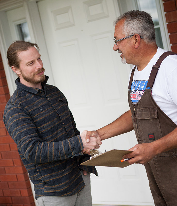 Two men shaking hands in front of a house